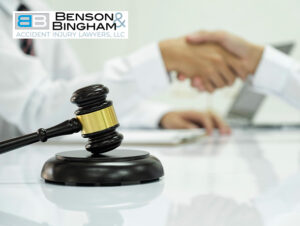 Foreground gavel with a handshake between two individuals in the background, indicative of a legal agreement or case resolution