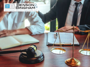 Lawyer and client discussing a case with a gavel and scales of justice on the table, pertaining to a settlement check