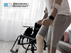 An individual with a leg injury and using crutches, with a wheelchair in the background, possibly recovering from being hit by falling debris