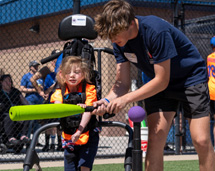 Teen Helping Young Girl On Mobile Stander Bat The Ball