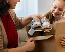 Volunteer Handing Pair Of Sandals To Young Girl