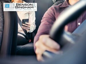 A passenger in a rideshare car using their phone while the driver steers, related to Rideshare Car Accidents and liability in such incidents