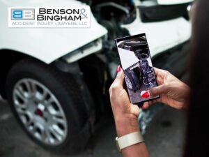 A person viewing a photo of a car accident on their phone, highlighting the importance of Trademark and Copyright laws in personal injury marketing.